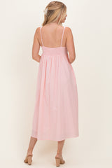 woman wearing a backless pink striped midi dress with thin straps and a smocked bodice