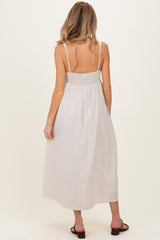 woman wearing a white striped maternity maxi dress with a smocked back and adjustable straps