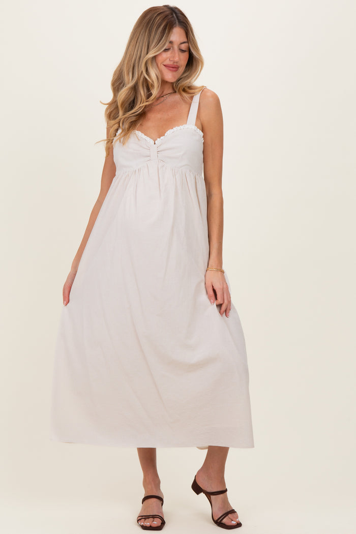 woman wearing a white striped maternity maxi dress with a twisted front and spaghetti straps, showing her baby bump