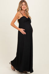 woman wearing a black maternity maxi dress with a tie detail and holding her baby bump