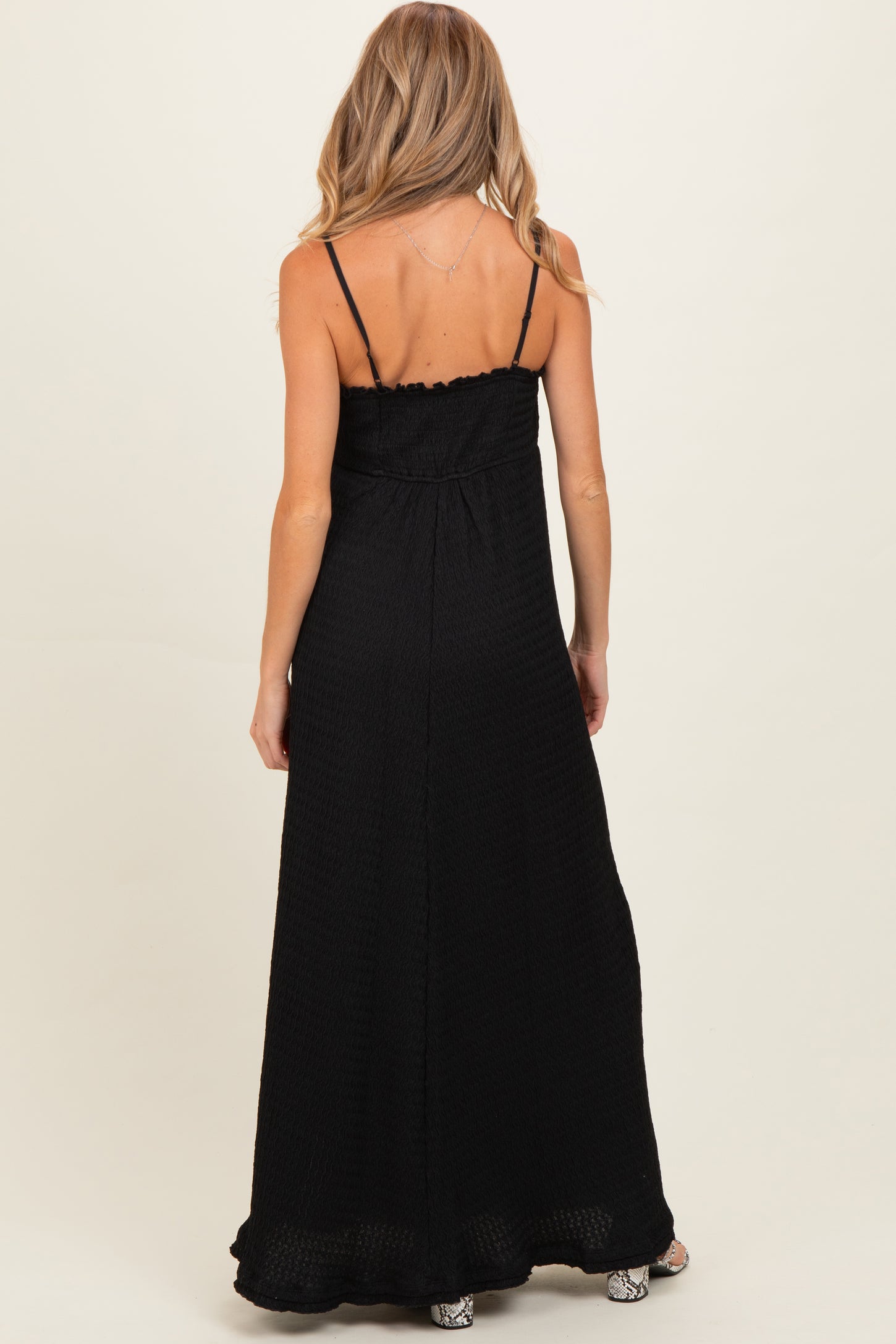 woman wearing a black maternity maxi dress with spaghetti straps, showing a comfortable fit at the back