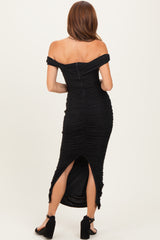 woman wearing a black off-the-shoulder dress with ruched detailing and a thigh-high slit, viewed from the back