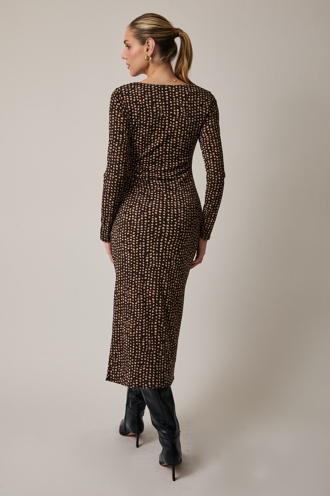 woman wearing a fitted brown midi dress with a geometric print and long sleeves, viewed from the back