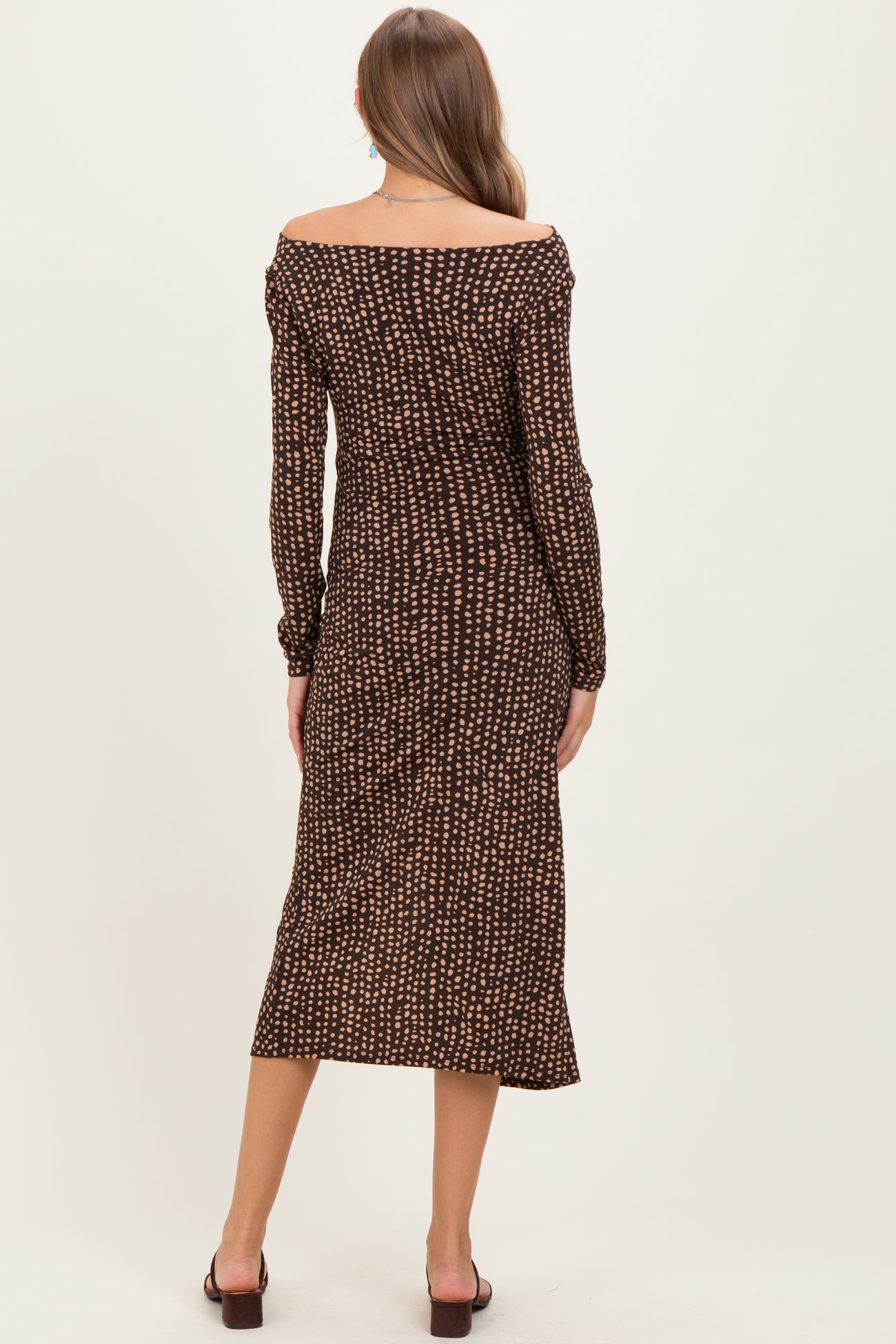 woman wearing a brown off-shoulder maternity dress with a patterned design, showing a fitted silhouette and mid-calf length