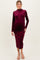 woman wearing a burgundy long sleeve maternity dress with a fitted silhouette and high neckline, showing her baby bump