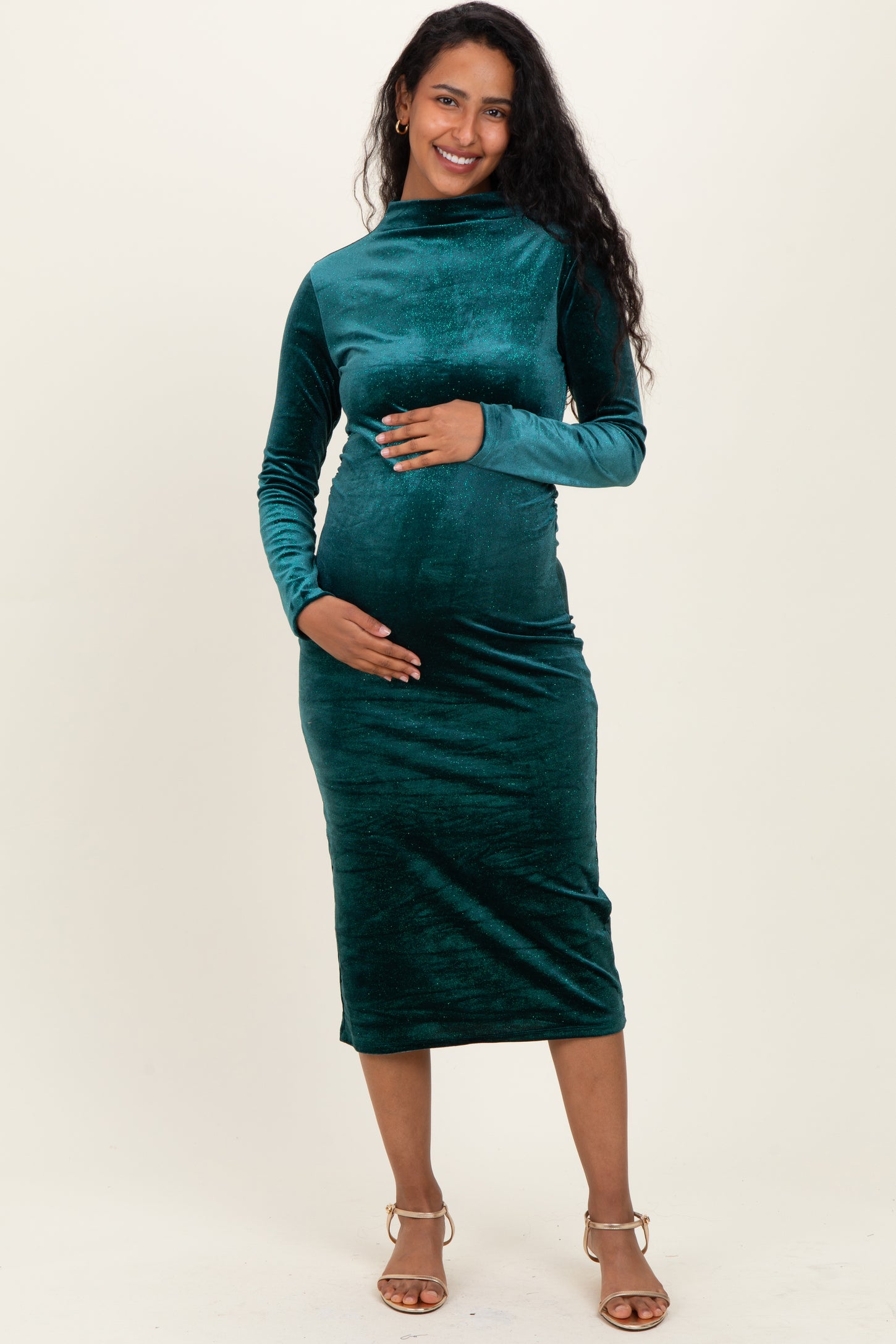 woman wearing a dark green long sleeve maternity dress and holding her baby bump