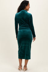 woman wearing a green velvet long sleeve maternity dress, showcasing a fitted silhouette and midi length, showing her baby bump