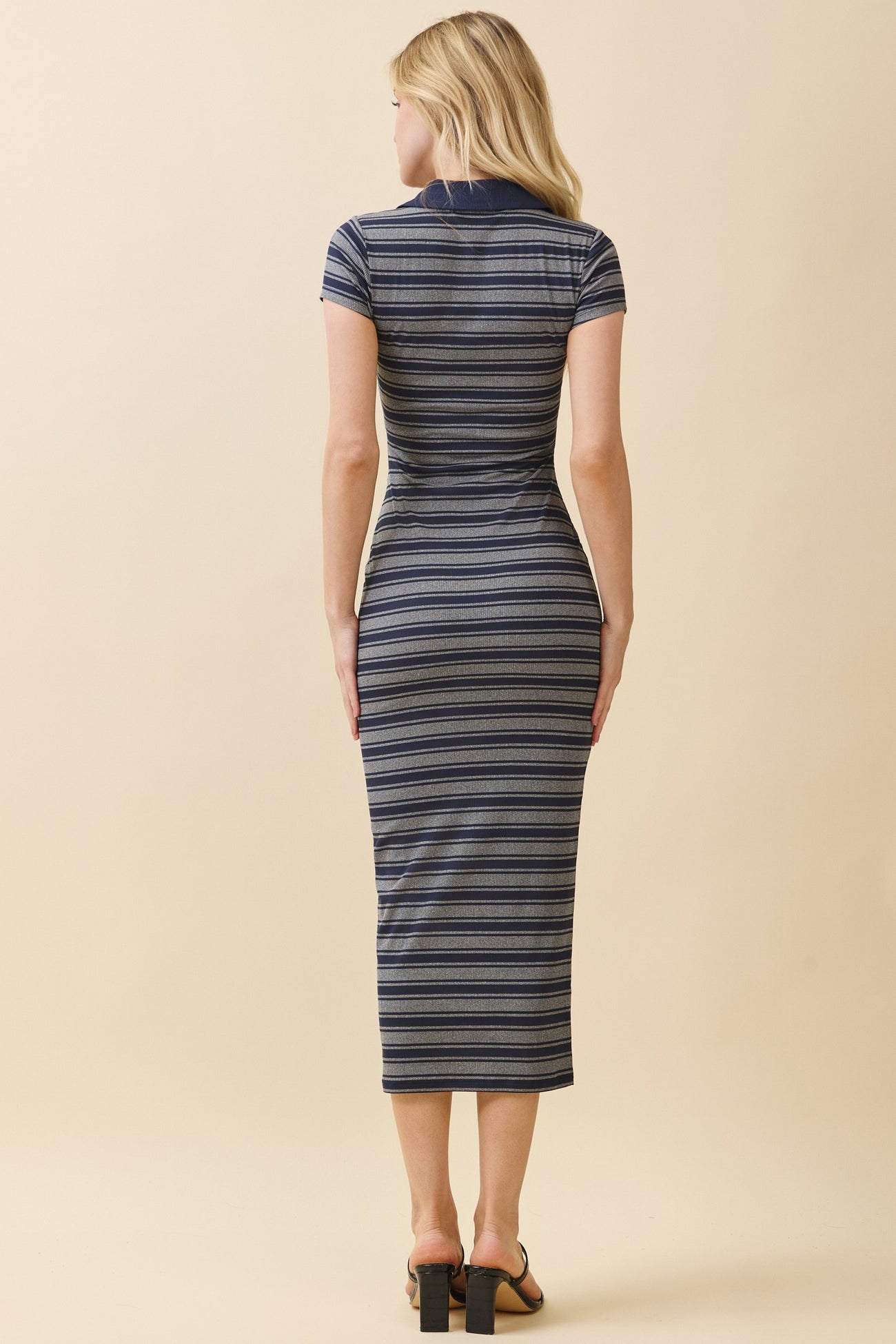 woman wearing a fitted navy and white striped midi dress with short sleeves and a collar, viewed from the back