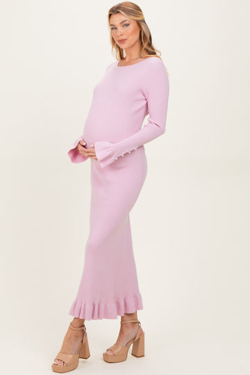 woman wearing a light pink ribbed maternity dress with a ruffled hem and bell sleeves, showing her baby bump