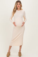 woman wearing a light beige ribbed maternity dress, posing with her baby bump visible