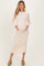 woman wearing a light beige ribbed maternity dress, posing with her baby bump visible