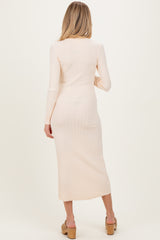 woman wearing a light peach long sleeve ribbed maternity dress, showing a fitted silhouette and midi length