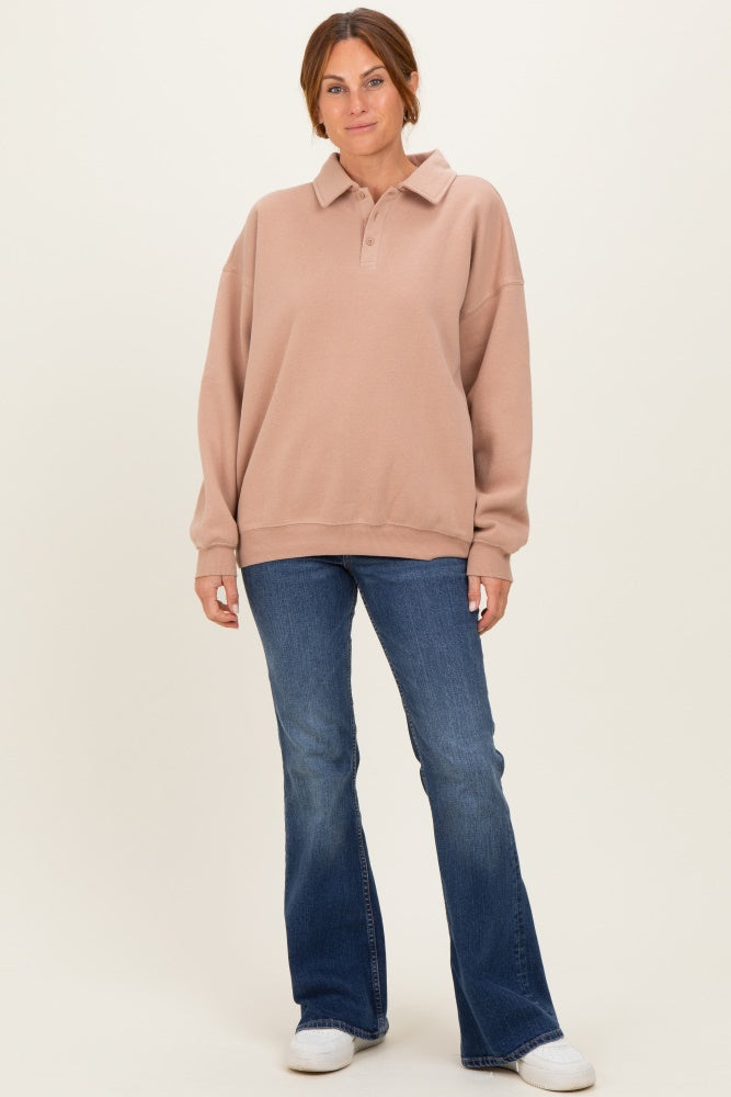 woman wearing a light pink oversized polo sweatshirt with long sleeves and blue flared jeans