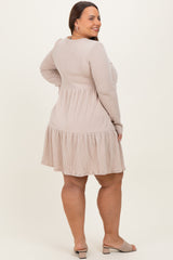 plus size woman wearing a beige ribbed long sleeve dress with a flared tiered skirt and a fitted waist