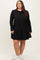 woman wearing a black long sleeve plus size dress with a tiered skirt and white sneakers