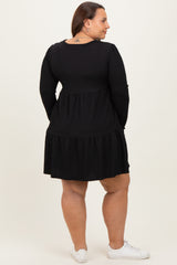 woman wearing a black long sleeve plus size dress with a tiered skirt and round neckline, seen from the back