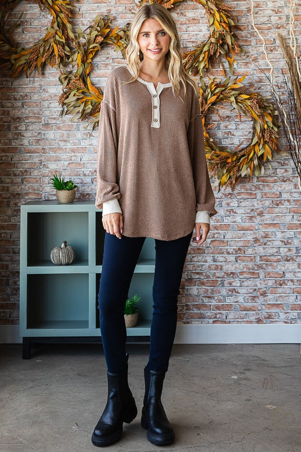 woman wearing a brown striped long sleeve henley top with buttons, paired with dark skinny jeans and black ankle boots