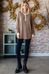 woman wearing a brown striped long sleeve henley top with buttons, paired with dark skinny jeans and black ankle boots