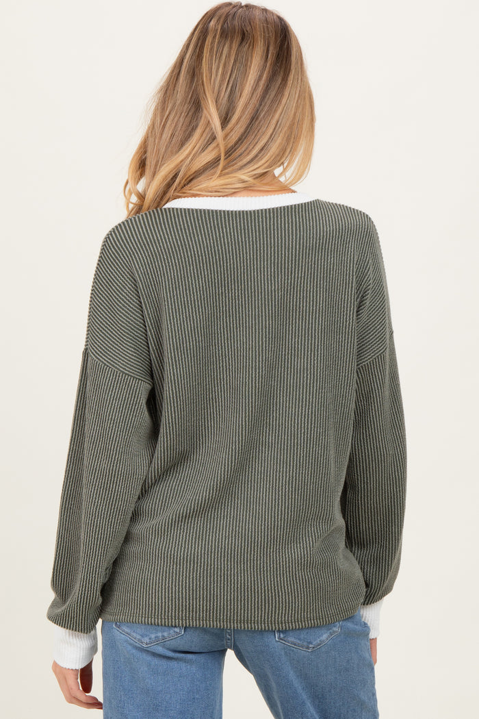 woman wearing an olive green ribbed maternity sweater with a white neckline, seen from the back