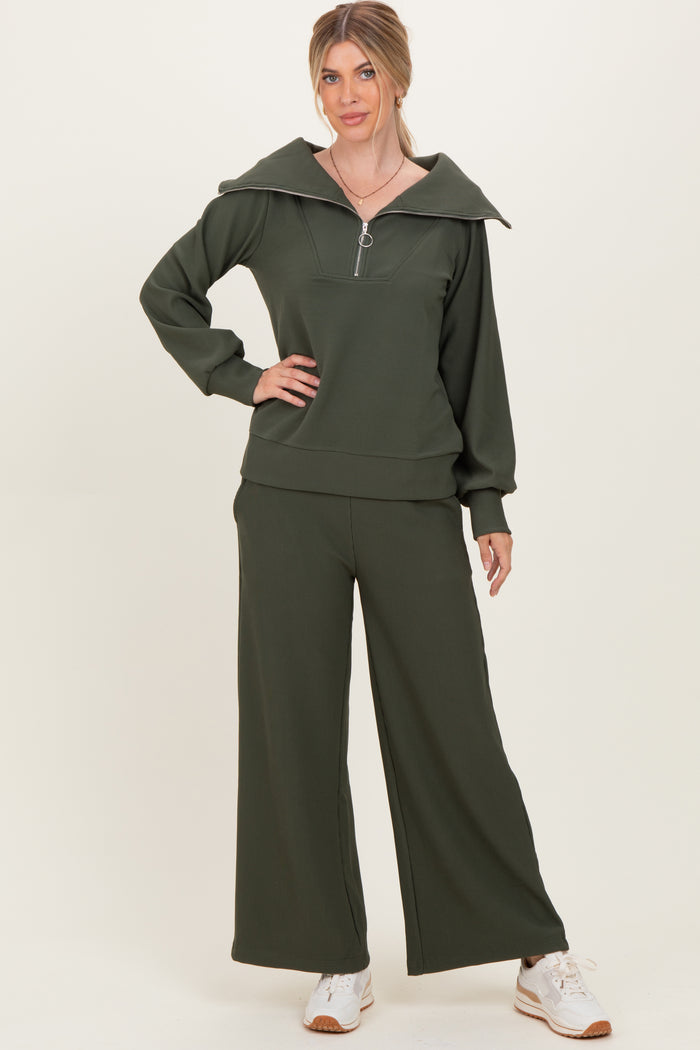 woman wearing a dark green ribbed zip-up sweatshirt and matching wide-leg pants with a relaxed fit