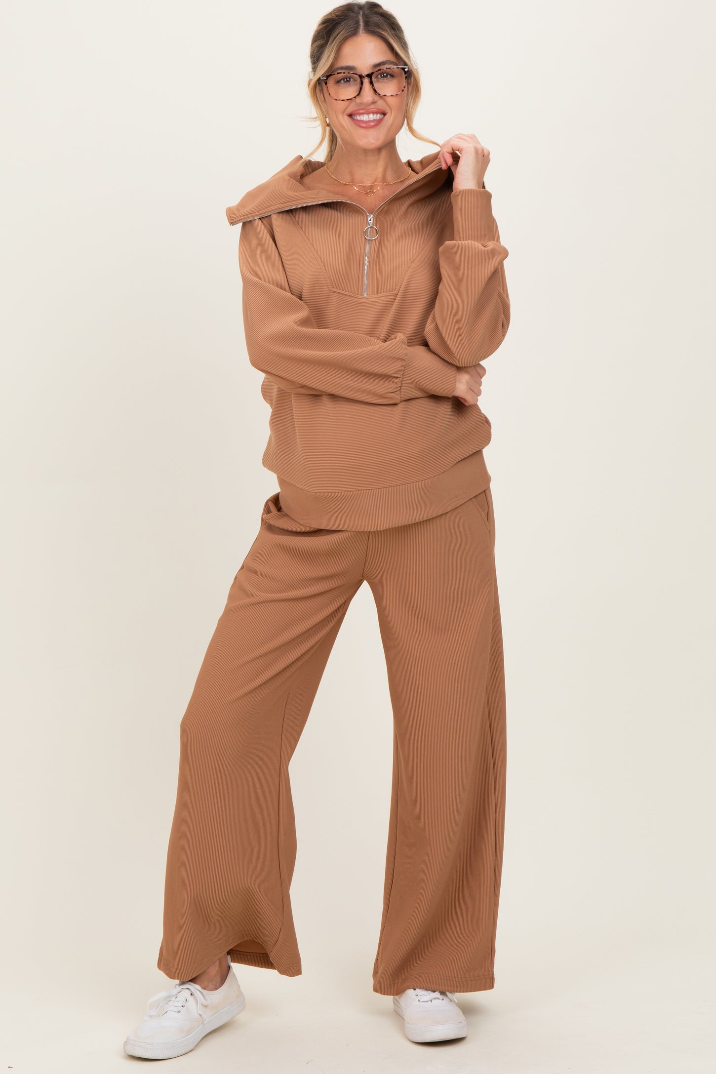 woman wearing a tan maternity hoodie with a zipper and matching wide-leg pants, styled for comfort and casual wear