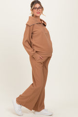 woman wearing a brown long sleeve maternity tracksuit with a hood and wide leg pants, showing her baby bump