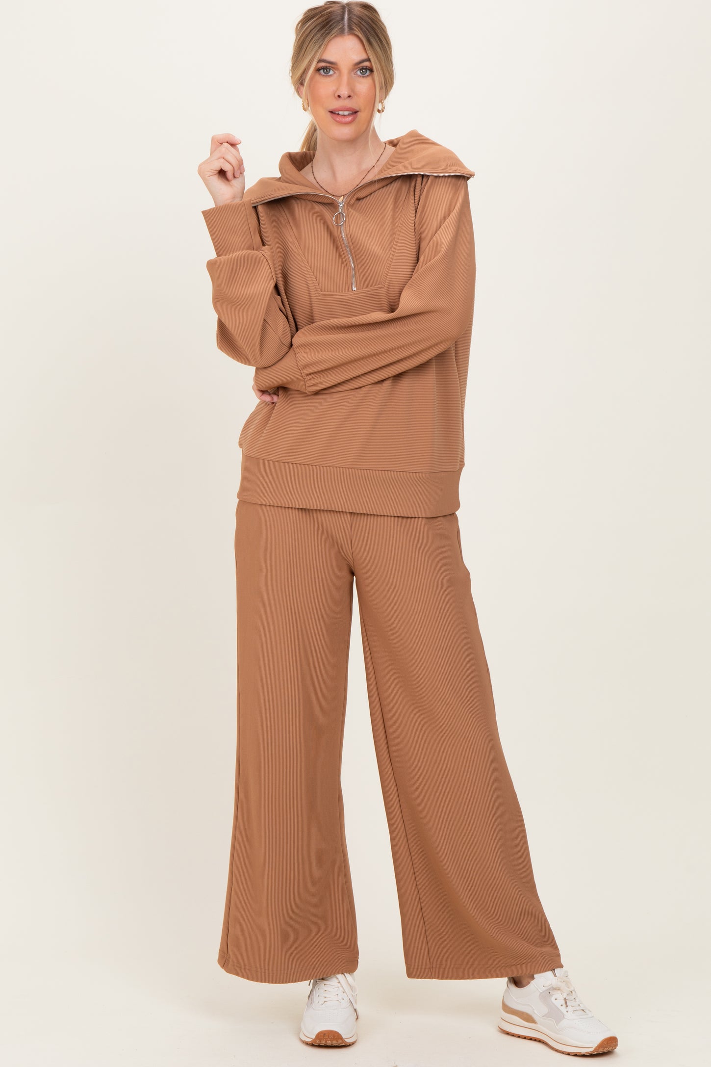 woman wearing a tan ribbed loungewear set with a zip-up hoodie and wide-leg pants