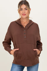 woman wearing a brown maternity hoodie with a button-up neckline and front pocket