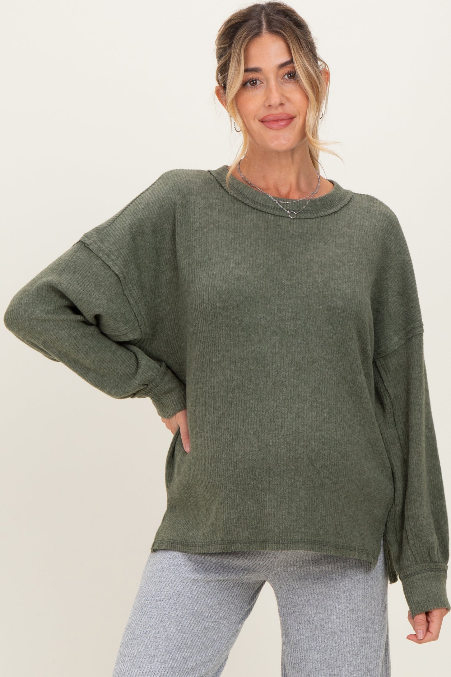 woman wearing a green oversized ribbed maternity sweater with relaxed fit and side slits