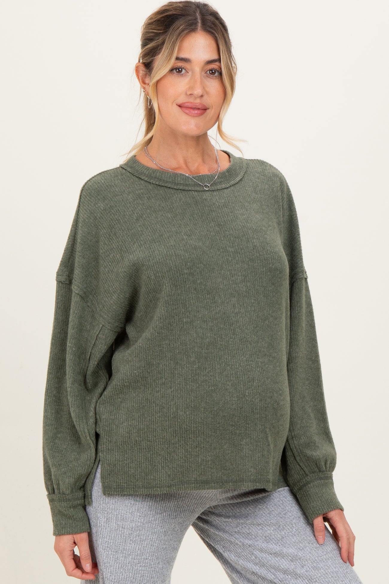 woman wearing a green oversized maternity sweater with long sleeves and a relaxed fit, showcasing her baby bump