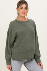 woman wearing a green oversized maternity sweater with long sleeves and a relaxed fit, showcasing her baby bump