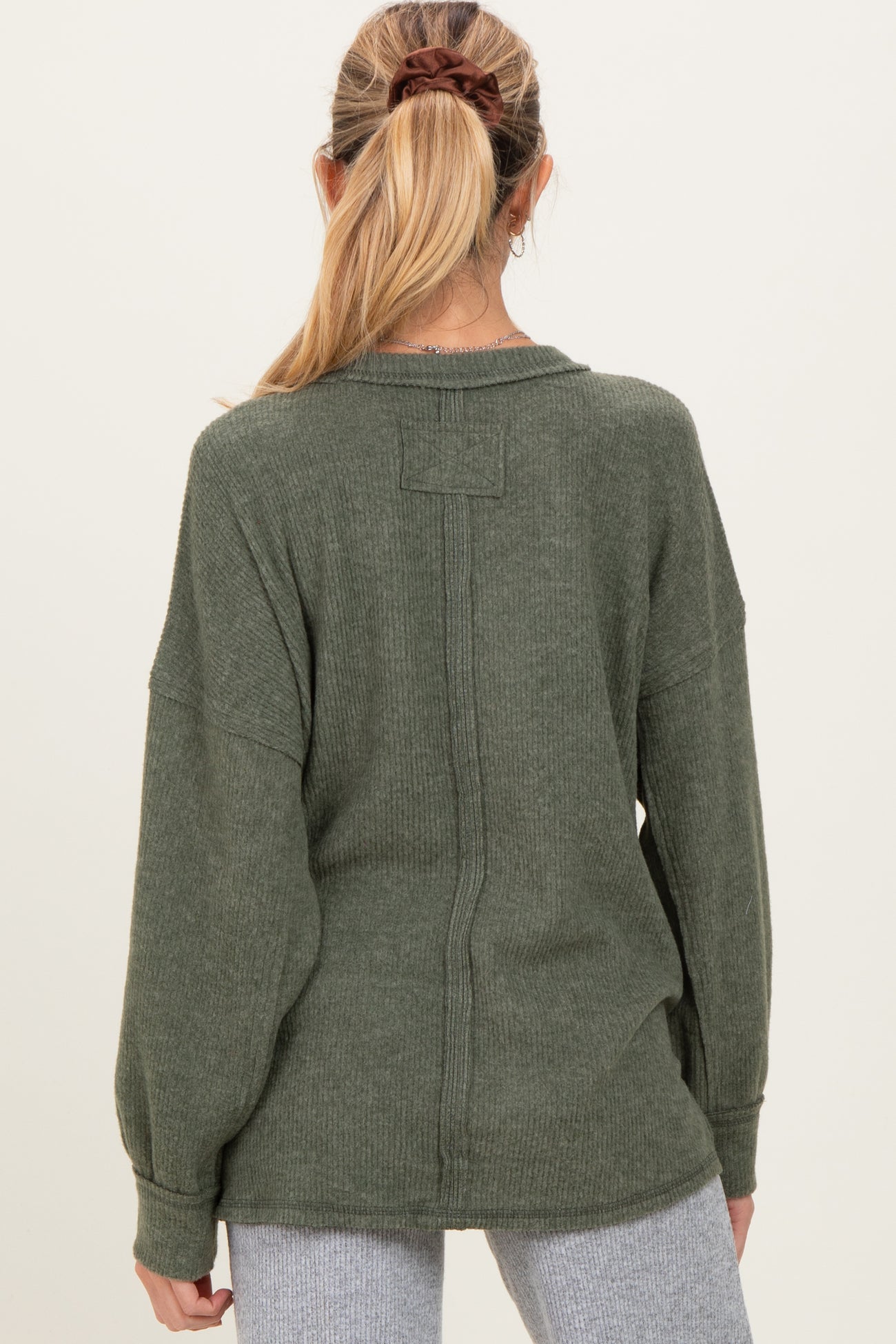 woman wearing a green maternity sweater with a relaxed fit and dropped shoulders, seen from the back