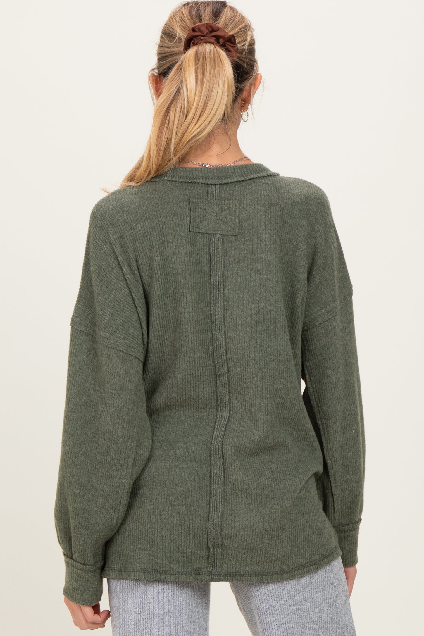 woman wearing a green maternity sweater with a relaxed fit and dropped shoulders, seen from the back