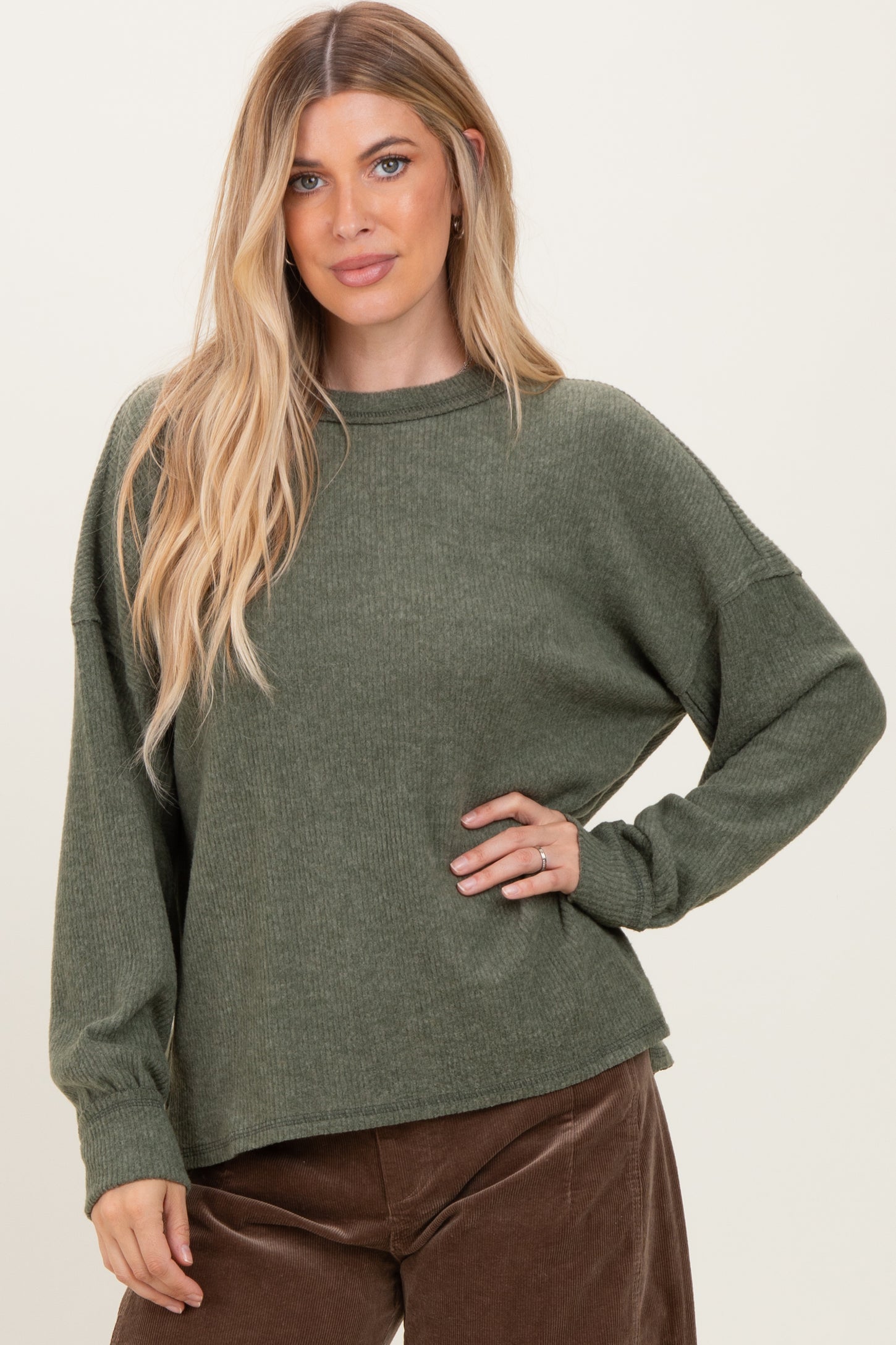 woman wearing a dark green ribbed long sleeve oversized sweater with a relaxed fit