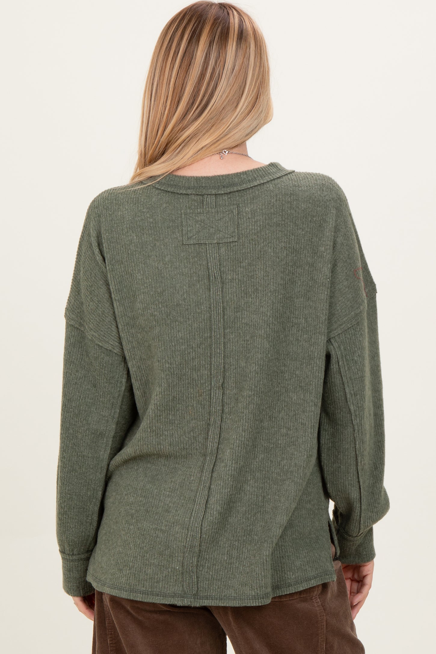 woman wearing a relaxed fit olive green long sleeve sweater with a back seam detail