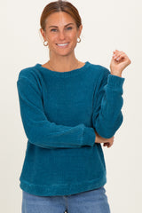 woman wearing a teal chunky knit long sleeve sweater with a relaxed fit and crew neckline
