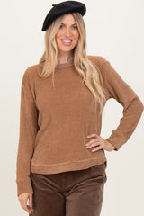 woman wearing a brown ribbed long sleeve sweater and black beret, posing with hand on hip