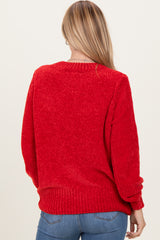 woman wearing a red textured oversized sweater with long sleeves, viewed from the back