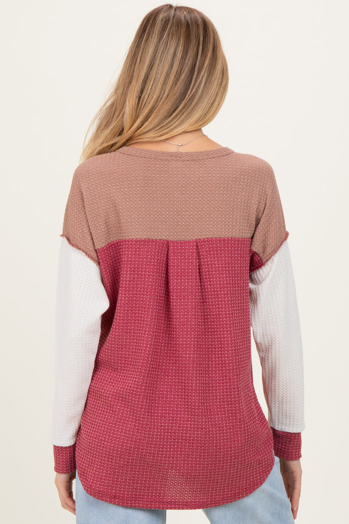 woman wearing a color-blocked maternity top in pink, brown, and white with a relaxed fit and back pleat detail