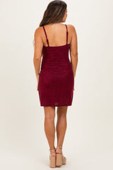 woman wearing a burgundy sparkly maternity dress with adjustable straps, showing a fitted silhouette from the back