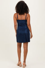woman wearing a navy blue sparkly mini dress with thin straps, shown from the back