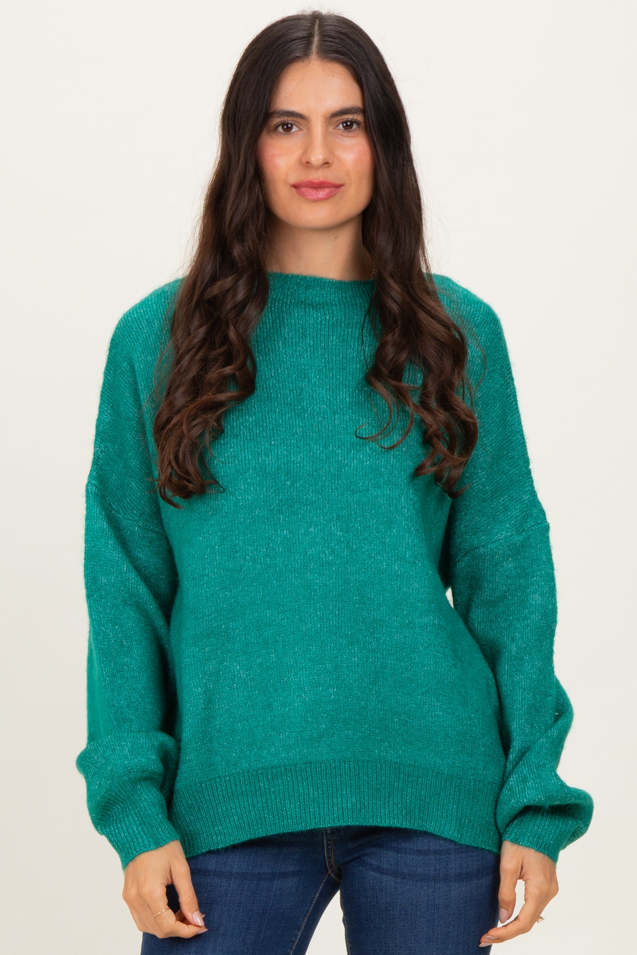 woman wearing a teal oversized sweater with long sleeves and relaxed fit, paired with dark skinny jeans