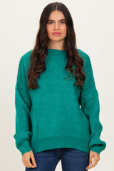 woman wearing a teal oversized sweater with long sleeves and relaxed fit, paired with dark skinny jeans