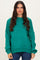 woman wearing a teal oversized sweater with long sleeves and relaxed fit, paired with dark skinny jeans