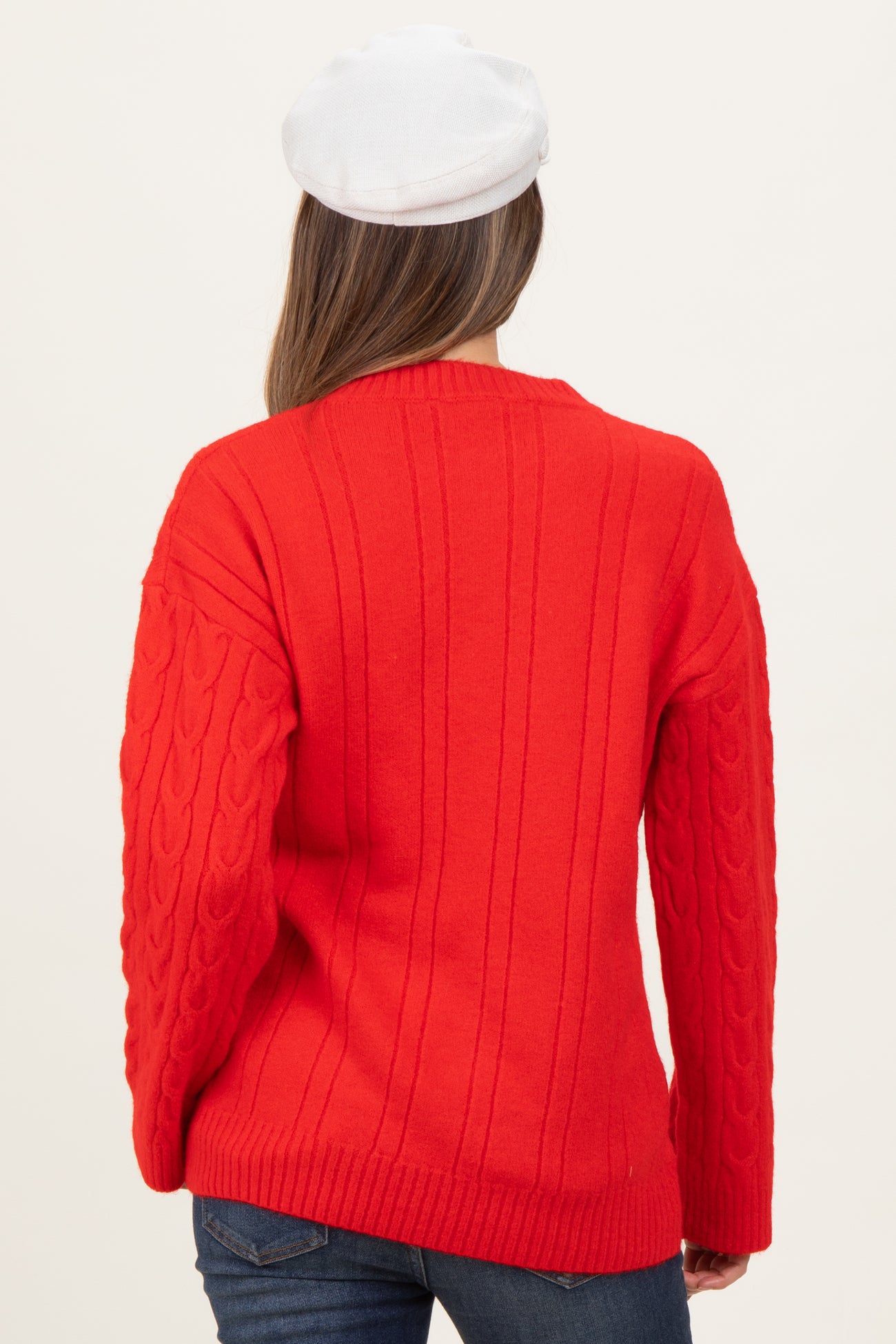 woman wearing a red cable knit maternity sweater, seen from the back, with a relaxed fit and long sleeves