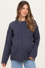 woman wearing a dark navy chunky knit maternity sweater with a relaxed fit and cable knit design