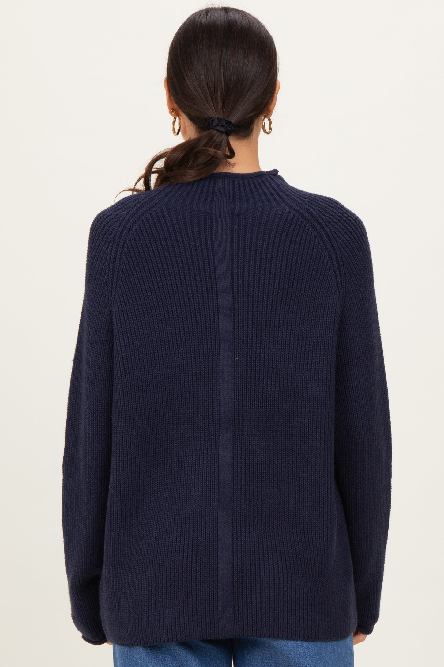 woman wearing a navy blue oversized ribbed sweater, showing the back view with a relaxed fit and dropped shoulders