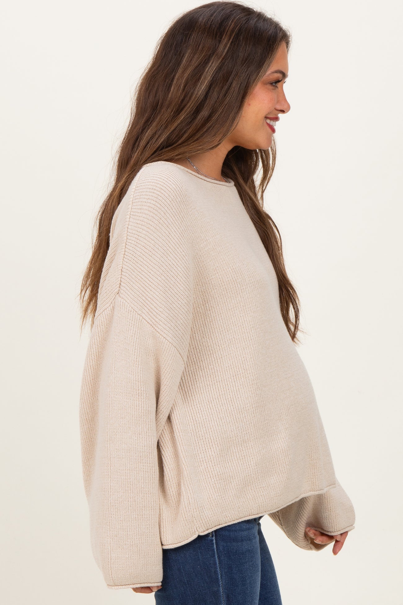 woman wearing a beige oversized maternity sweater with a relaxed fit and visible baby bump