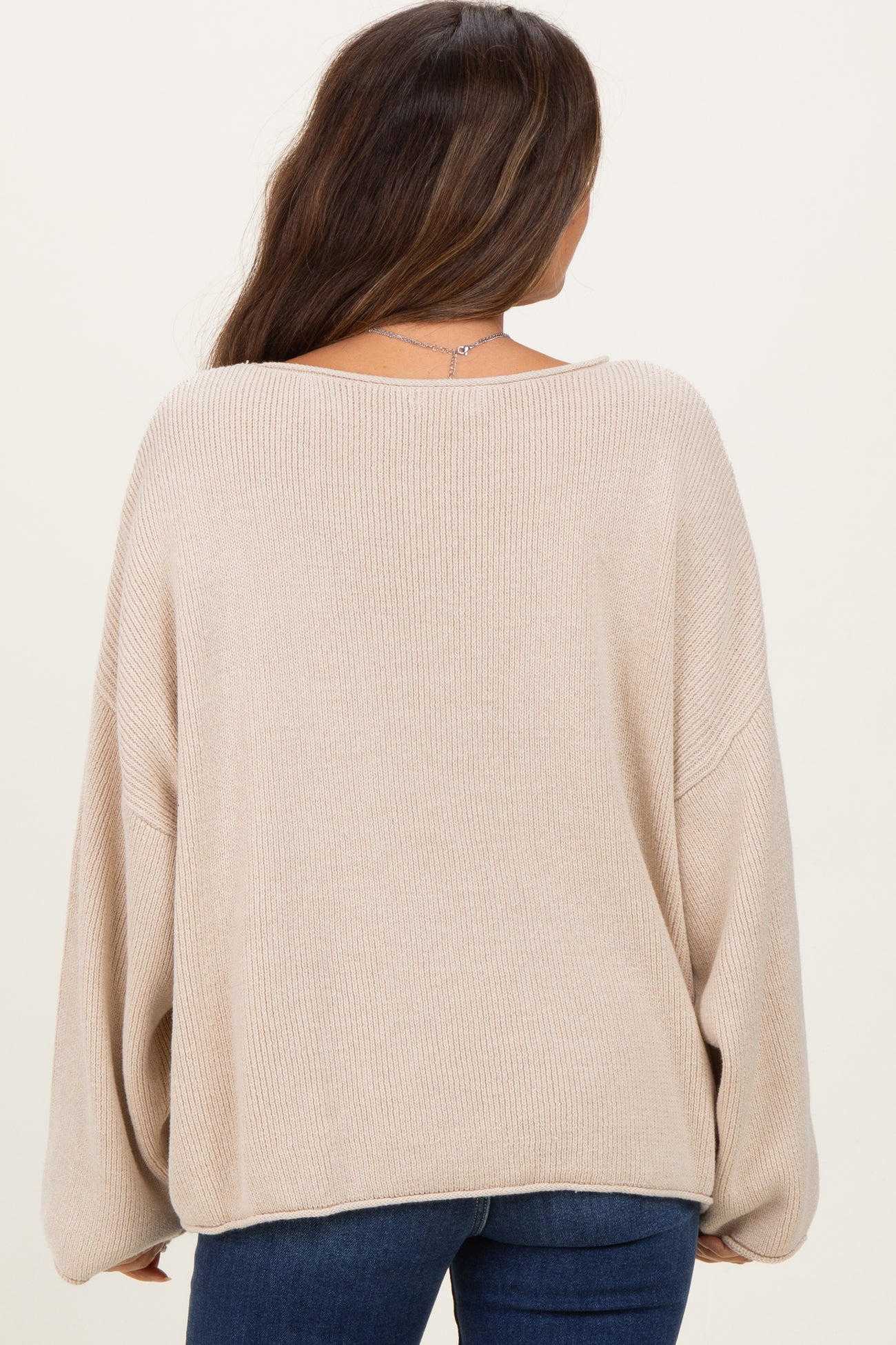 woman wearing a light beige oversized maternity sweater with a relaxed fit and long sleeves