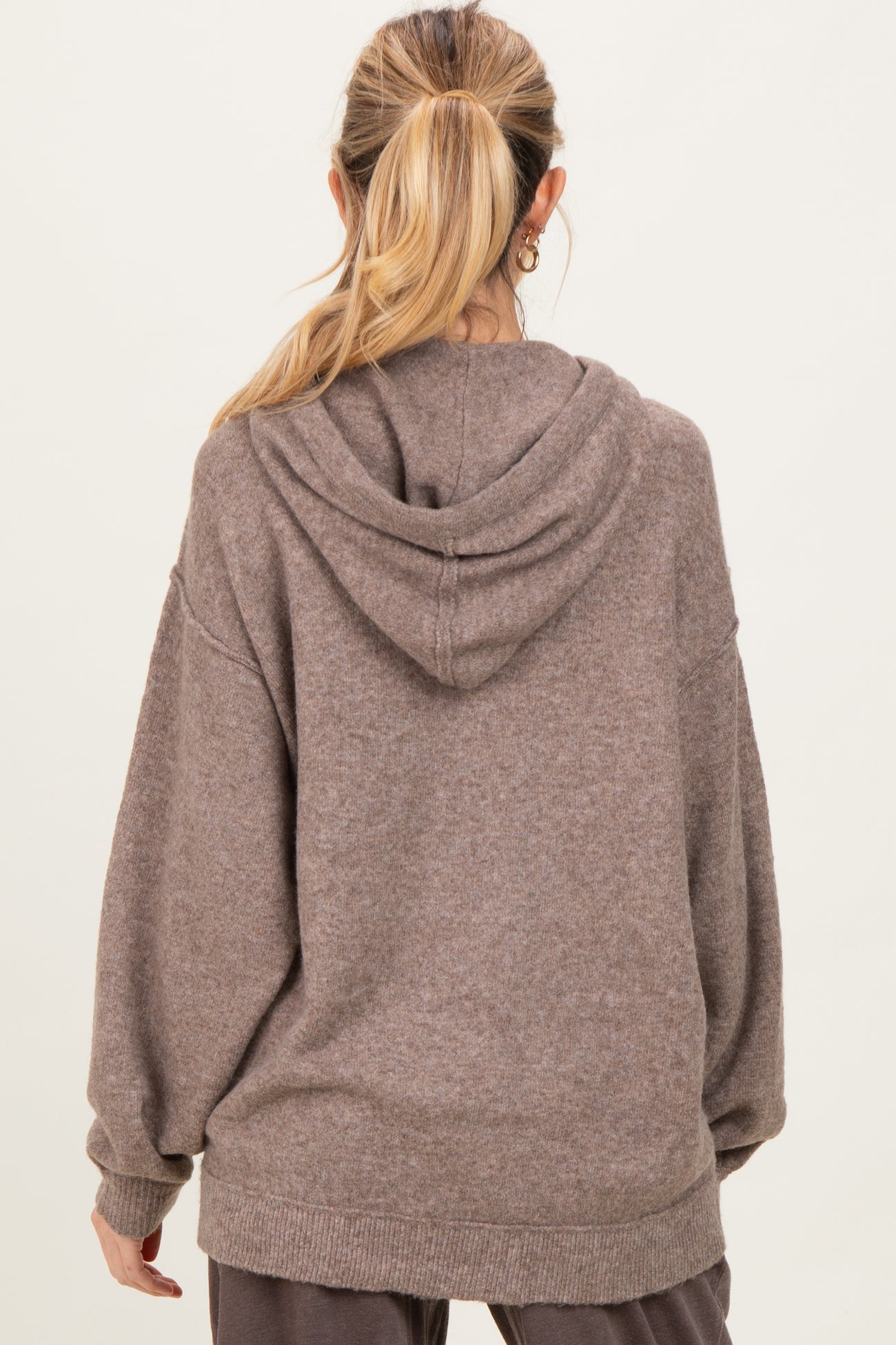 woman wearing a brown oversized maternity hoodie with a hood, viewed from the back